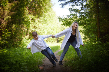 Funny mother with dreadlocks and fat boy happy walking in the woods on a sunny summer day