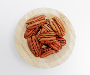 wooden bowl of pecan nuts on white background