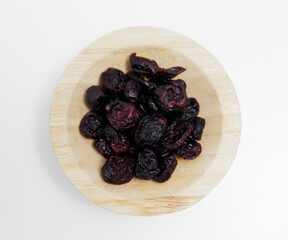 wooden bowl of dried cranberries on white background