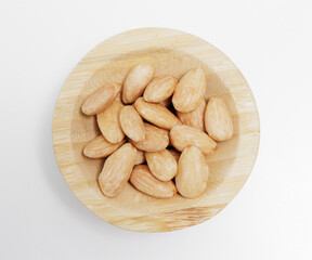 wooden bowl of roasted almond nuts on white background