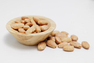 wooden bowl of roasted almond nuts on white background