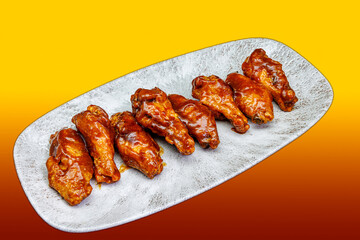 Plate of barbecued chicken wings on a yellow and red gradient background