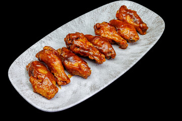 Plate of barbecue chicken wings on black background