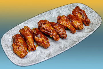 Plate of barbecued chicken wings on a yellow and light blue gradient background