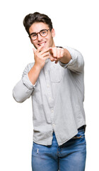 Young handsome man wearing glasses over isolated background Laughing of you, pointing to the camera with finger hand over mouth, shame expression