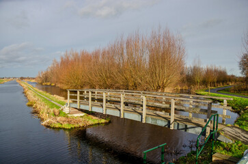 Gouda, The Netherlands, January 6, 2023: narrow pedestrian bridge leading to a hiking trail into...