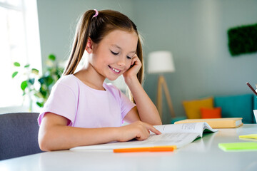 Photo of lovely cheerful intelligent girl sitting chair read book study courses materials apartment inside
