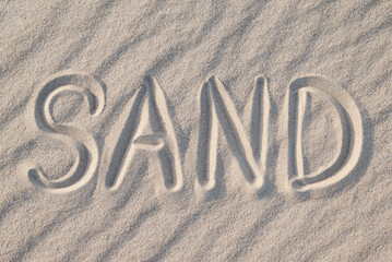 Inscription Sand on sand beach. Concept of beach, summer, vacation