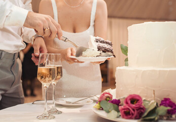 The wedding cake. Wedding Cake with blur bride and groom background. Wedding cake with luxury decorated in wedding party. White, three-tiered, decorated with flowers.