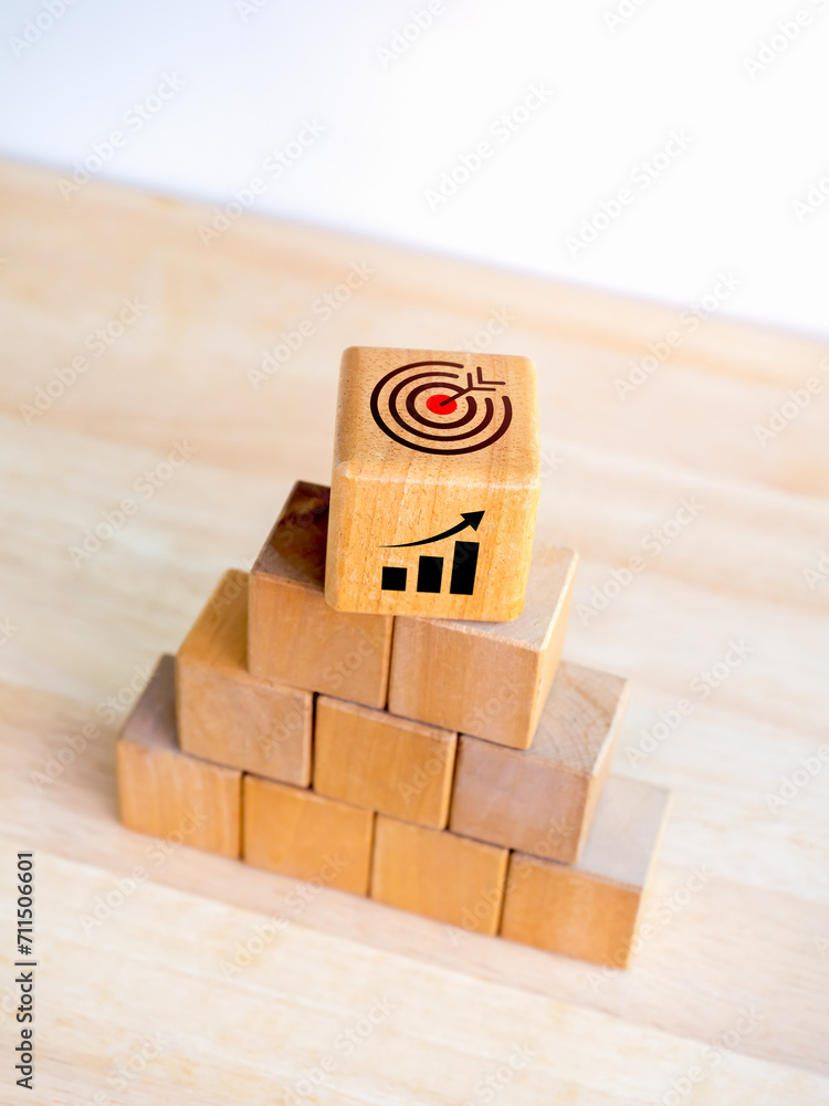 Poster target icon and growth graph symbol on top of wooden cube blocks stack as pyramid shape on white bac