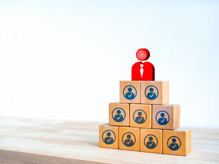 Business leadership, the leader goal, organization development concepts. Big red businessman with target icon on top of colleague or company staff on wooden blocks pyramid shape on white background.