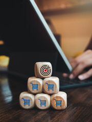 Target icon on top of wooden cube block stack pyramid shape with shopping cart icons while...