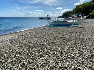 Fishing boats anchored along the sandy beach on a bright sunlight.