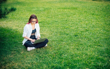 Naklejka na ściany i meble Focused young businesswoman freelancer typing on her laptop working outdoors.