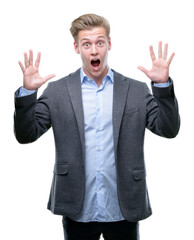 Young handsome blond business man celebrating crazy and amazed for success with arms raised and open eyes screaming excited. Winner concept