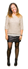 Beautiful middle age woman wearing fashion sweater sticking tongue out happy with funny expression. Emotion concept.