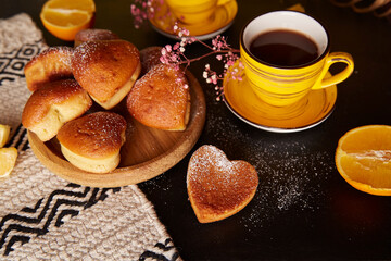 Aesthetics tea time with yellow cups and homemade heart shaped muffins. Cupcakes with orange flavour for Valentines Day breakfast.