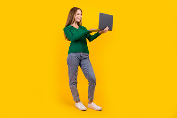 Full body size photo of cheerful girl loves learning new knowledge studying online with netbook by acer isolated on yellow color background
