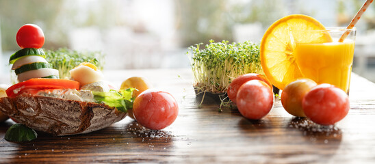 Healthy breakfast with freshly squeezed orange juice and colorful easter eggs on rustic wooden table. Horizontal close-up with short depth of field. - obrazy, fototapety, plakaty