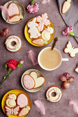 Fototapeta na wymiar Aesthetic happy Easter background, coffee time top view. Decorated glazed cookies, coffee, feathers flat lay. Spring background
