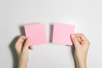 woman holding two empty pink sticky notes, making a choice. mockup, space for text