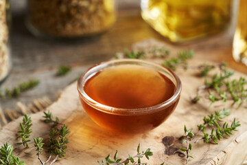 A bowl of herbal syrup with fresh thyme leaves