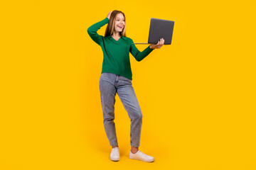 Full length body photo of young positive teenage girl watching video guide about maths exams tips isolated on yellow color background