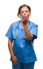 Middle age senior nurse doctor woman over isolated background looking at the camera blowing a kiss...