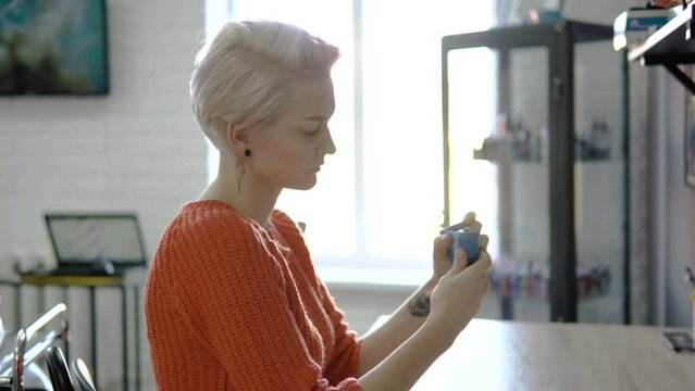Tattoo artist wraps tattoo machine, gun with adhesive tape.