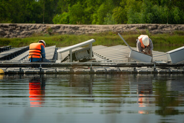 Both of technicians are currently evaluating and repairing the transmission terminals for electricity generated by solar energy in a floating solar power system.