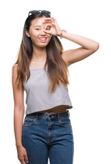 Fototapeta premium Young asian woman wearing sunglasses over isolated background doing ok gesture with hand smiling, eye looking through fingers with happy face.