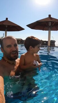 Father and son in the pool in summer playing enjoying the vacation