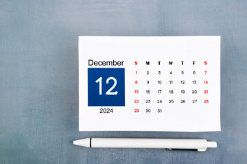 December Calendar 2024 page with pen on blue background.