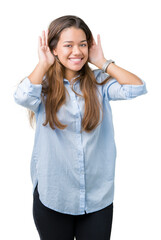 Young beautiful brunette business woman over isolated background Trying to hear both hands on ear gesture, curious for gossip. Hearing problem, deaf