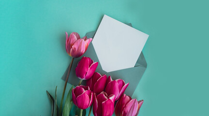 Empty white envelope copy space for your text or design with beautiful pink tulip bouquet on green...