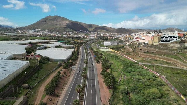Flying over the Northern road in Gran Canaria, Canary Islands from vertical drone, palm trees, road and the imposing Amagro Mountain of G&aacute;ldar, Filmed in Height with a drone in 4k