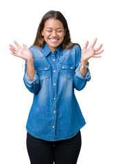 Young beautiful brunette woman wearing blue denim shirt over isolated background celebrating mad...