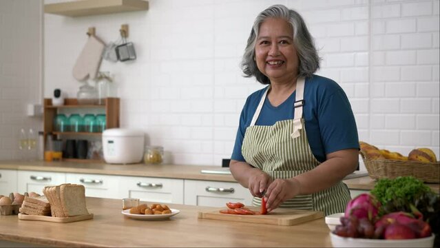portrait Senior woman cutting tomato for preparing cooking in kitchen