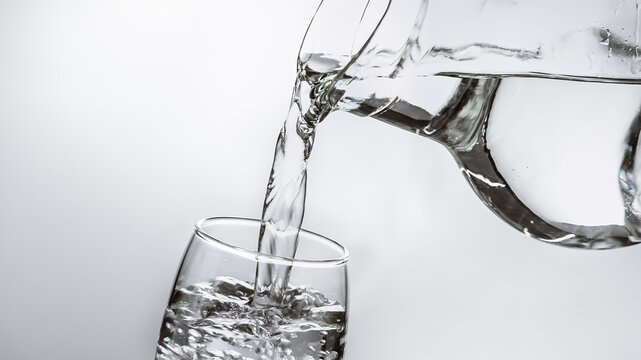 jarra de vidrio sirviendo agua en vaso de vidrio