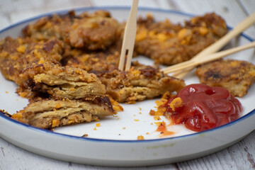 Vegan schnitzel appetizer made of seitan, gluten meat. White plate, wooden table