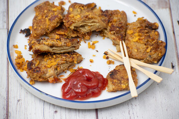 Vegan schnitzel appetizer made of seitan, gluten meat. White plate, wooden table