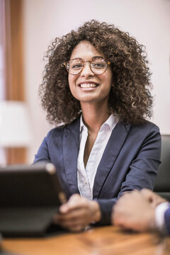 Woman of African descent in business attire sitting at desk and smiling in the camera. Cape Town, South Africa