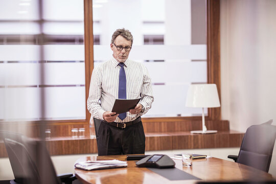Manager level employee of business start-up standing at his desk looking through documents. Cape Town, South Africa