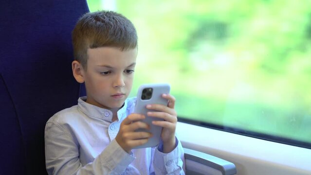 Pre teen boy traveling by train and using smartphone. Boy entertaining with net surfing viral videos or play games.