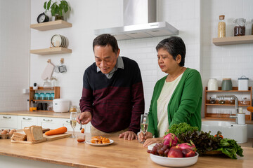 Mature couple have spending time with tasting sausage together in kitchen