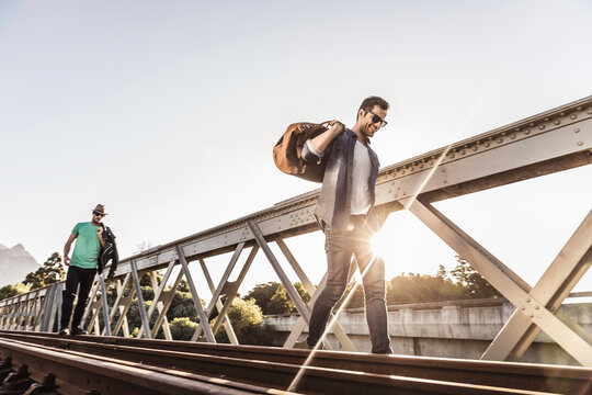 Group of friends walking across train bridge and hanging out hobo style. Paarl, South Africa