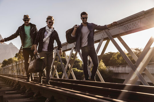 Group of friends walking across train bridge and hanging out hobo style. Paarl, South Africa