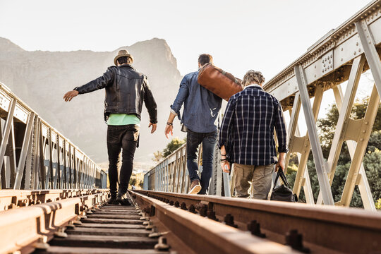 Group of friends walking across and hanging out on train bridge in the evening sun, Boho Style. Paarl, South Africa