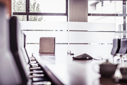 Conference room table and chairs with glass walls.