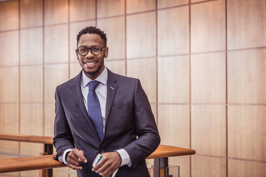 African business man standing casually in the office on his smart phone.